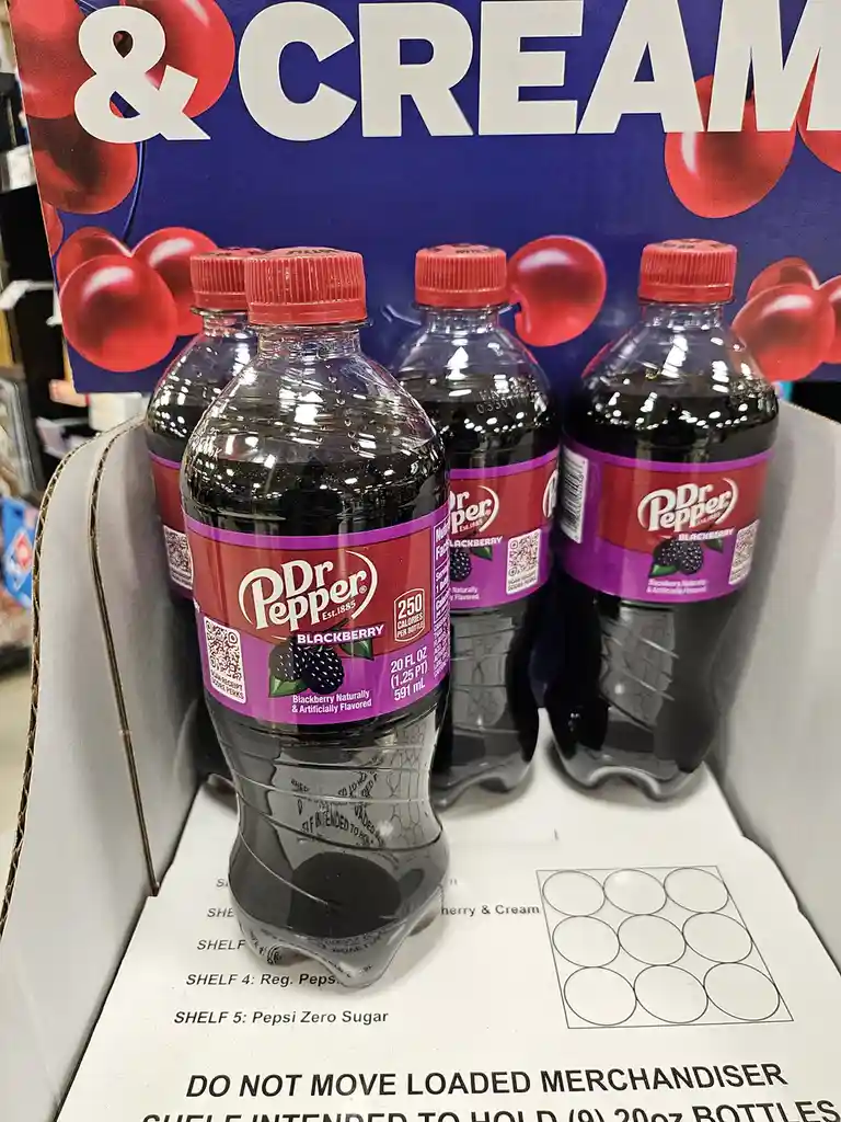 Several Dr Pepper Blackberry bottles sit in a store display, but the shelf label beneath them incorrectly lists 'SHELF 5…