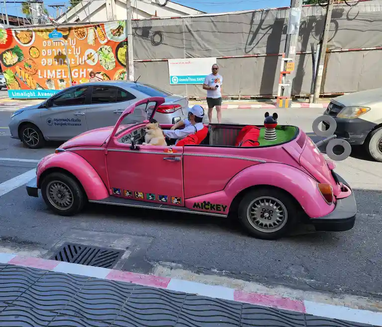 A bright pink, modified Volkswagen Beetle convertible with 'MICKEY' written on its side and Mickey Mouse-themed decorations…