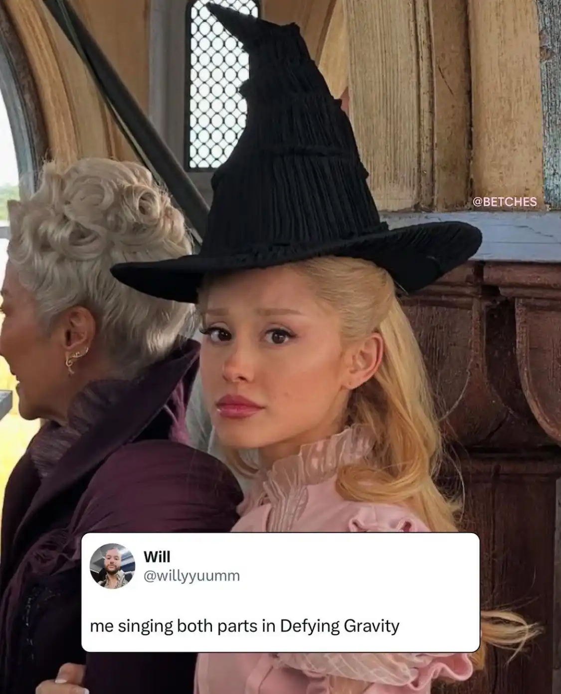 A woman with blonde hair wearing a black witch's hat looks over her shoulder with a confused or overwhelmed expression…
