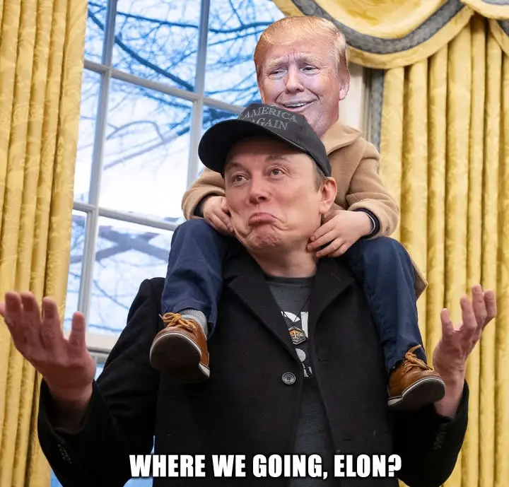 A man wearing a 'Make America Great Again' cap and a black coat has a child with a Donald Trump mask on his shoulders. The…