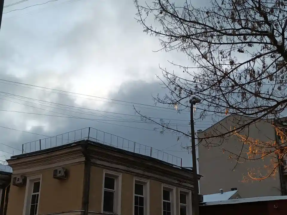 A photo of a cloudy sky with bare tree branches and buildings, with the text 'i'm not crying, you're crying' overlaid. The…