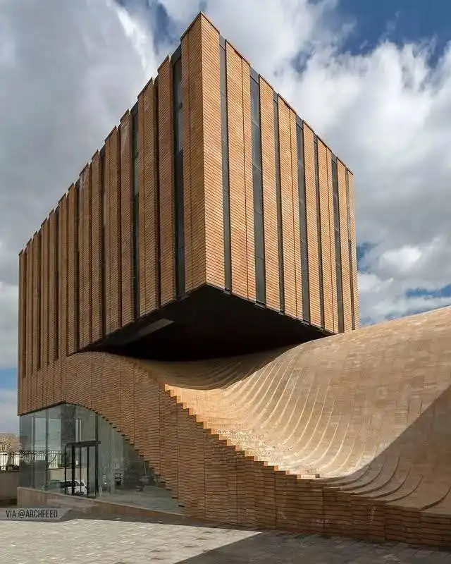 a modern architectural structure with a wooden facade appears to float above a curved, wave-like base made of similar wood…