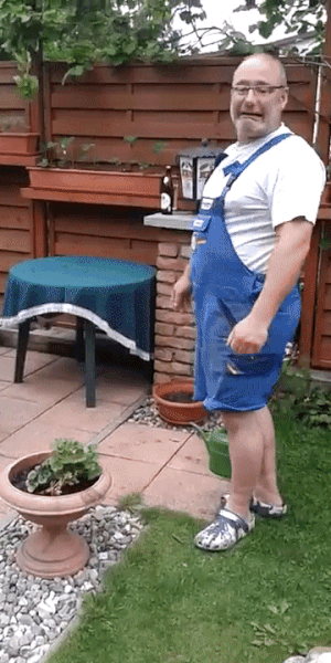 A man in blue overalls is shown in a backyard garden in a sequence of five panels. He starts standing upright, then bends to…