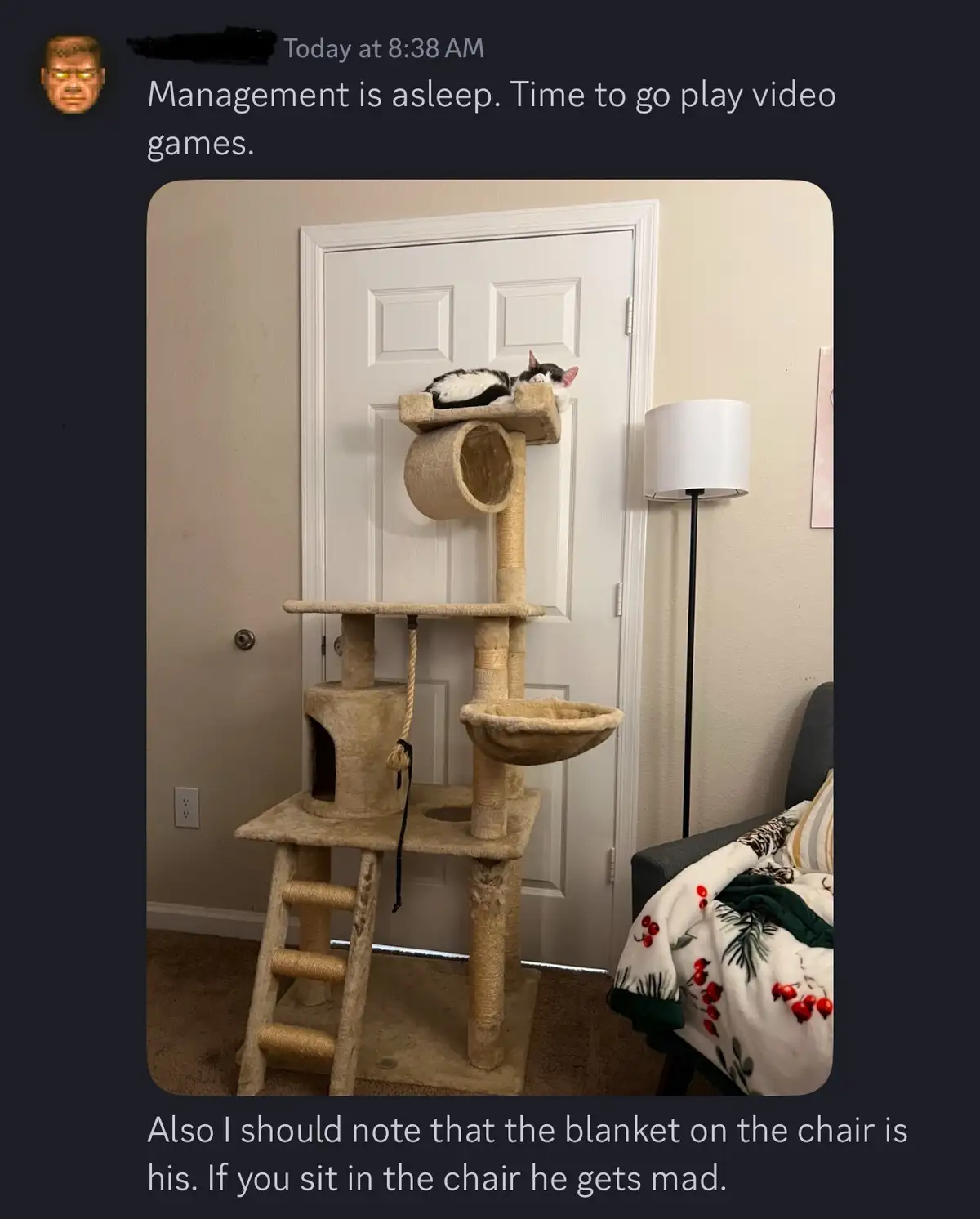 A black and white cat is sleeping on the top platform of a tall, multi-level cat tree positioned in front of a white door…