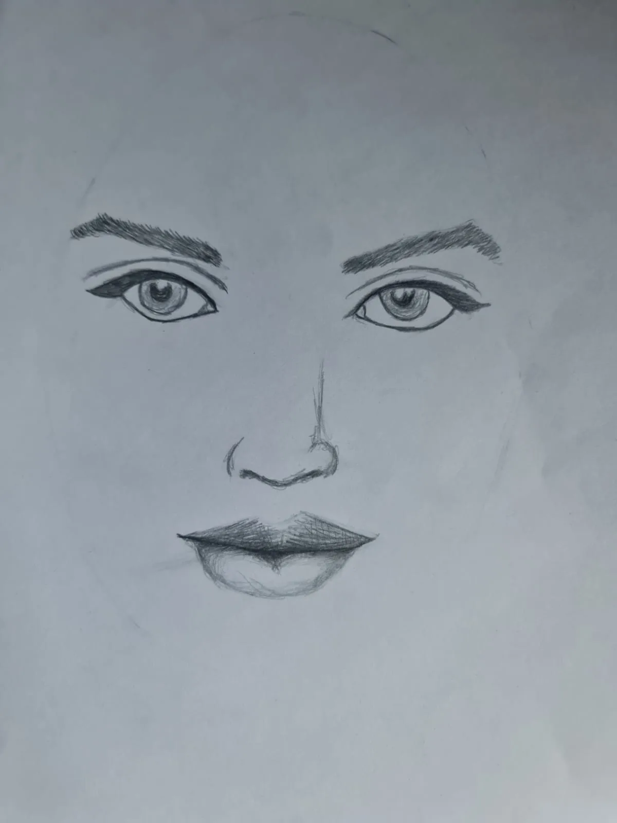 A pencil sketch of a human face, showing detailed eyes, eyebrows, nose, and lips, with faint pencil outlines suggesting the…