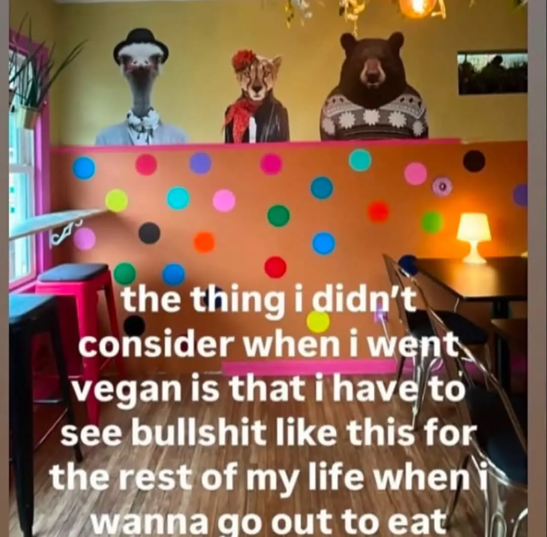 An image of a restaurant interior with a colorful polka-dot wall and three anthropomorphic animal murals above it: an…
