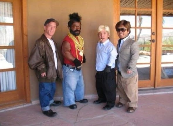 four men dressed as characters from the movie 'the incredibles' standing in front of a house. The man on the far left wears…