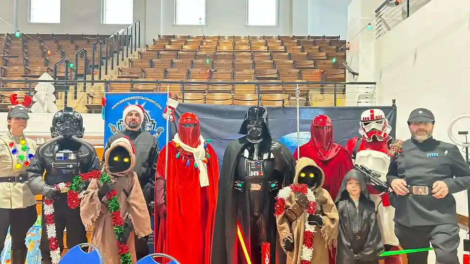 A group of people dressed as Star Wars characters, including Darth Vader, Stormtroopers, and other figures, are posing…