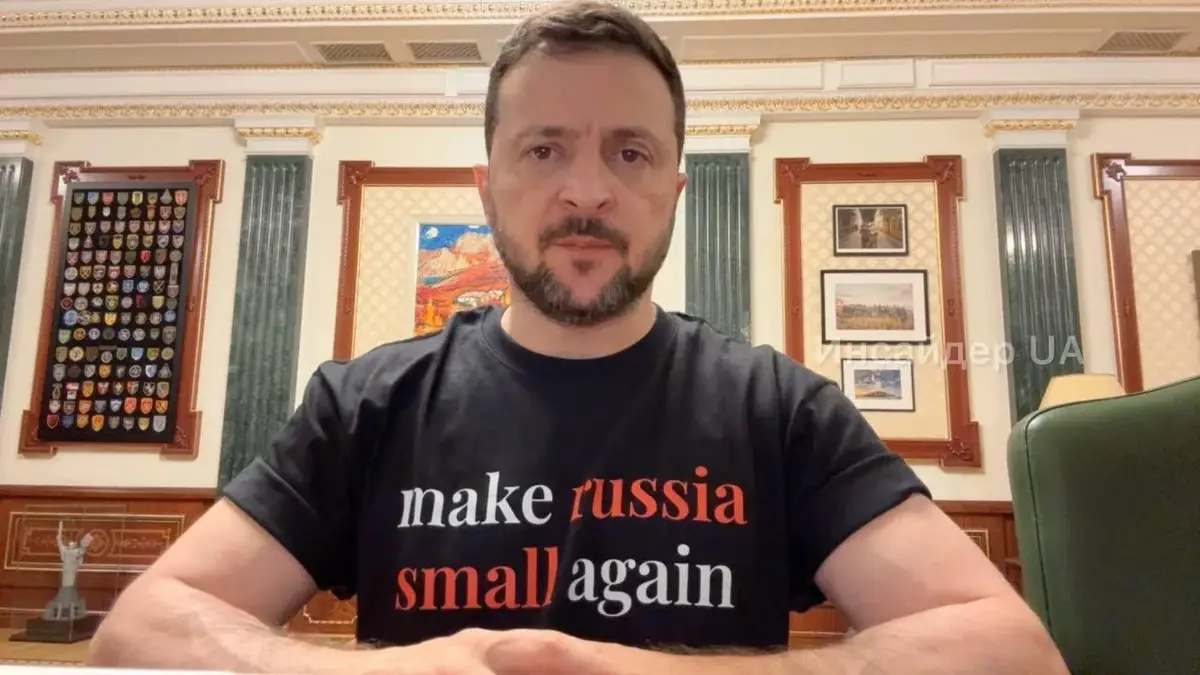 A man with a beard sits at a desk in an ornate room wearing a black t-shirt with the text 'make russia small again' in white…