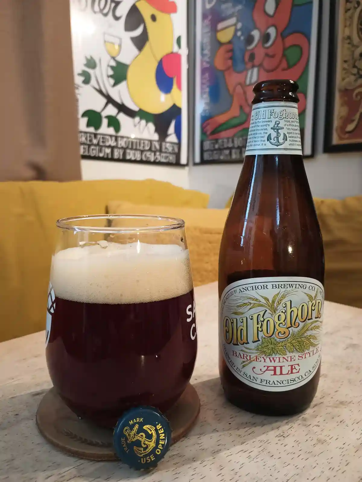 A bottle of Anchor Brewing Co.'s Old Foghorn Barleywine Style Ale sits next to a glass filled with the dark, foamy beer on a…