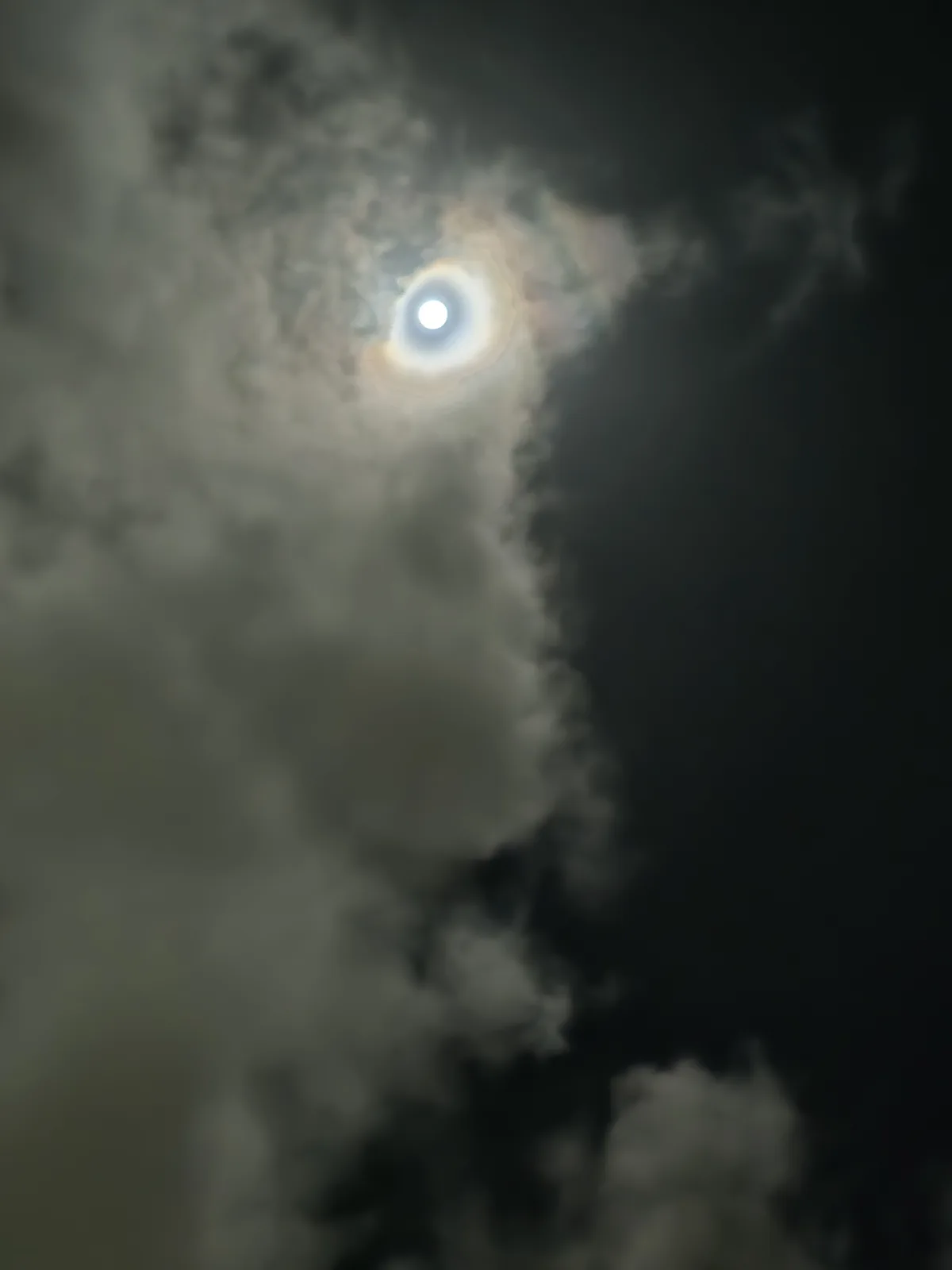 A bright, glowing orb, likely the moon or sun, is partially obscured by wispy, dark clouds in a night sky. The text 'i'm not…