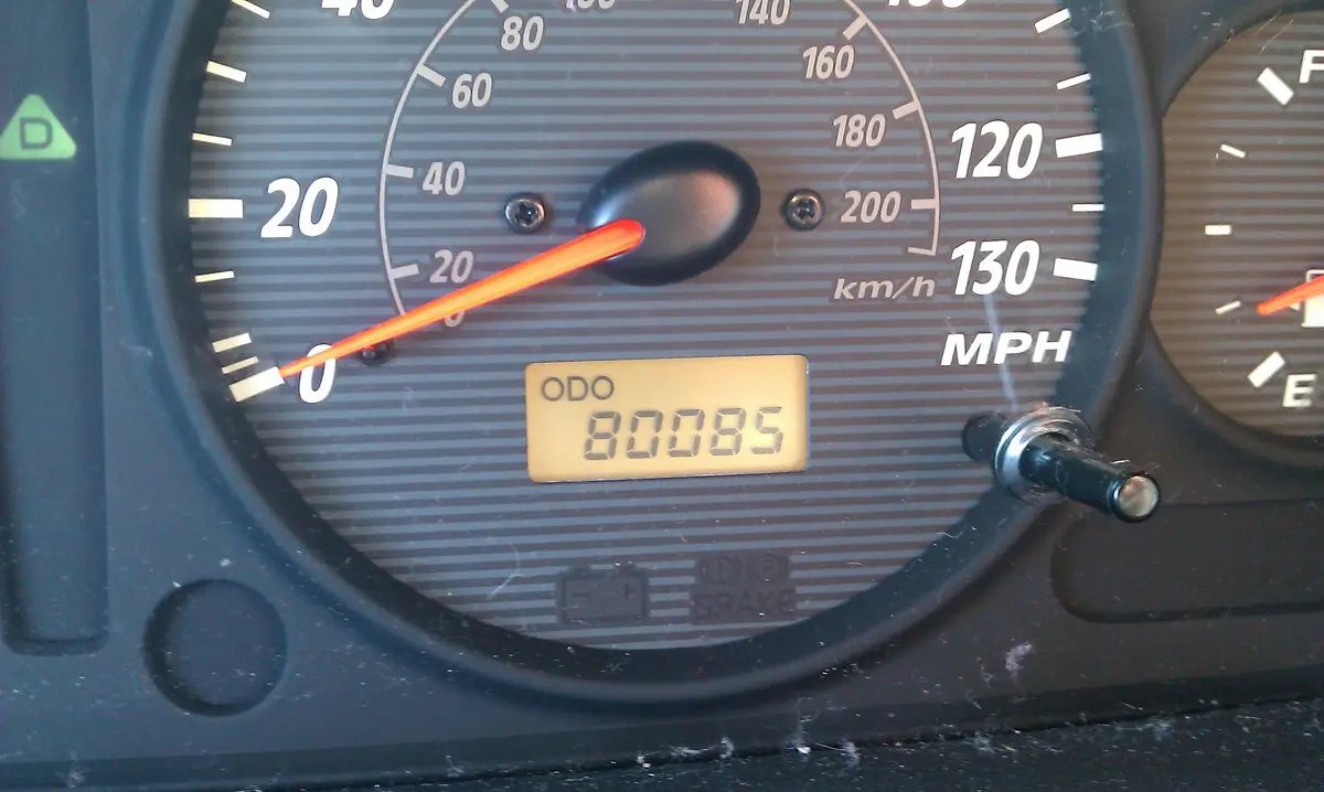 A close-up of a car's dashboard showing a speedometer with markings in km/h and MPH, and a digital odometer reading '80085'…