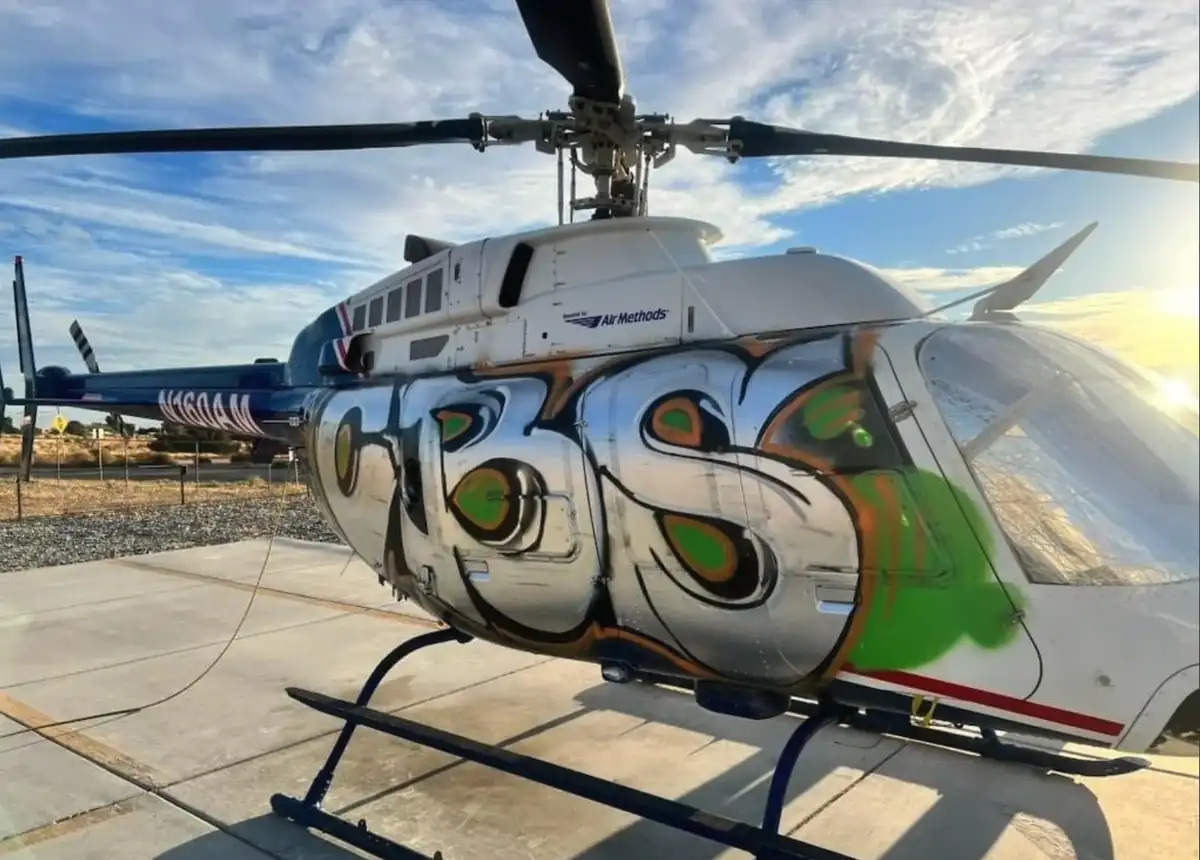 A white medical helicopter with 'Air Methods' branding sits on a concrete pad under a partly cloudy sky. The side of the…