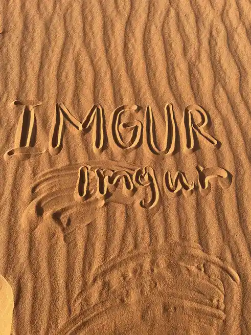 The image shows the word 'IMGUR' carved in uppercase letters into sand, with a second, more stylized and lowercase version…