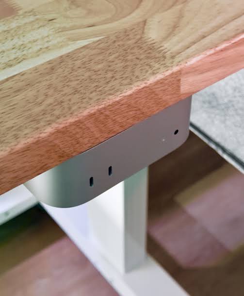 a close-up photo of a modern wooden table with a sleek metal support bracket underneath, featuring small indicator lights…