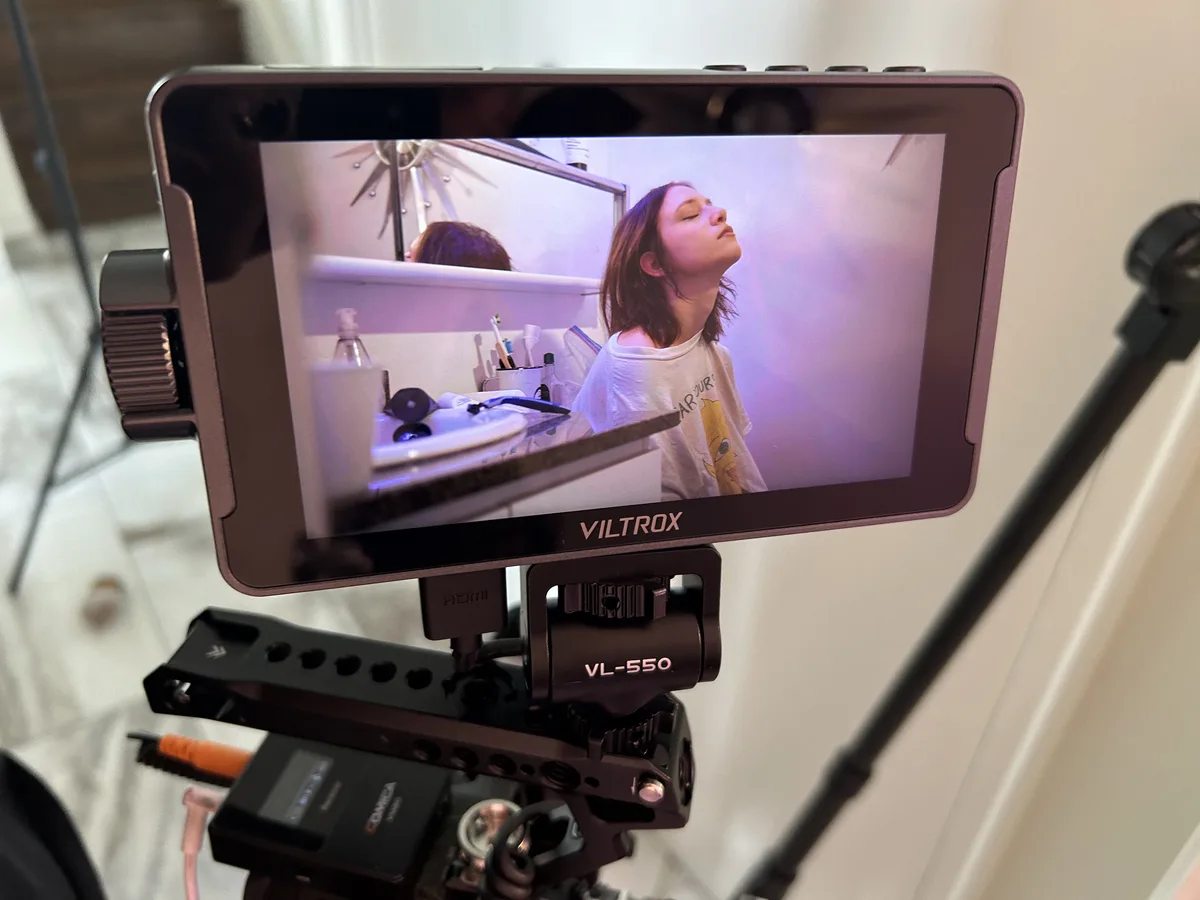 A VILTROX VL-550 monitor displays a video of a young woman with her eyes closed and head tilted back, appearing relaxed in a…