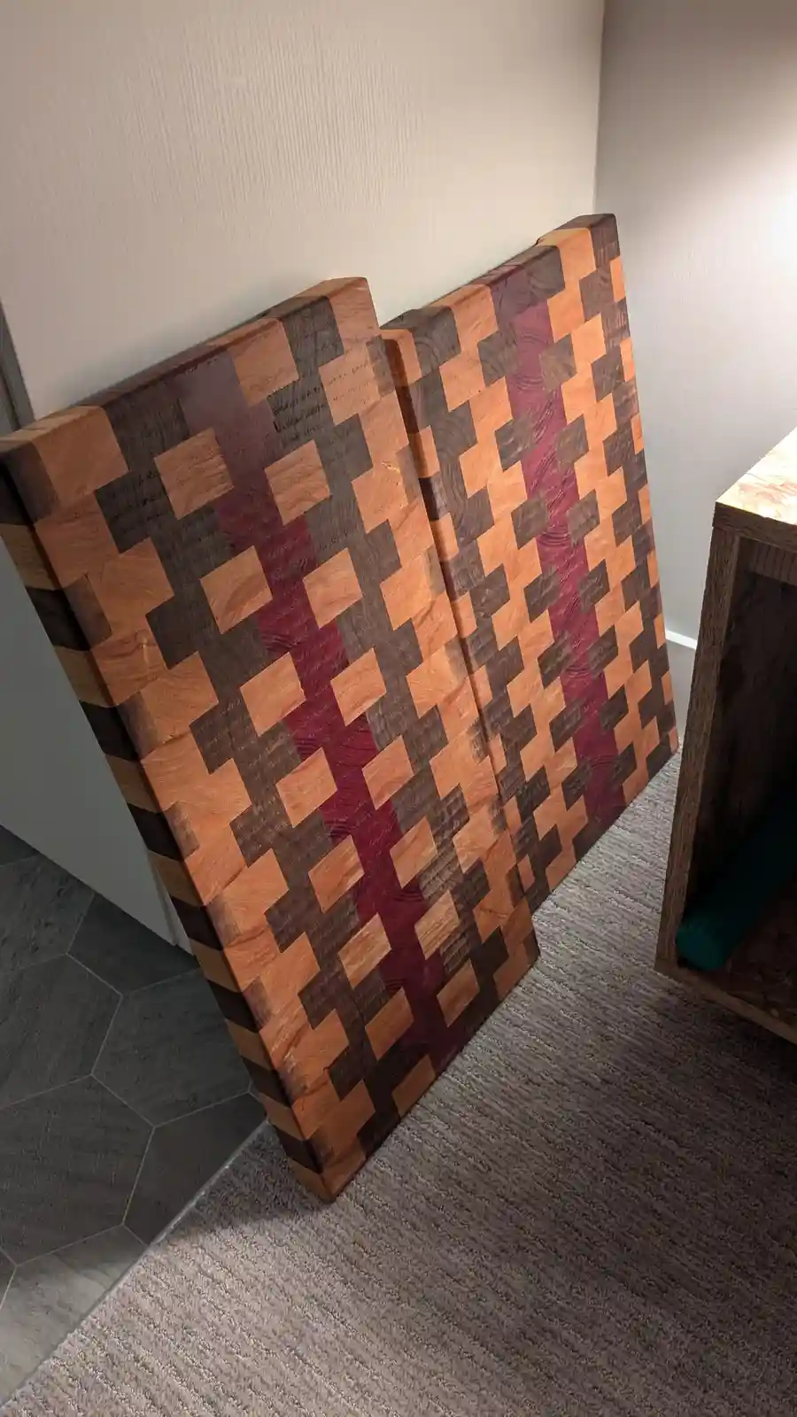Two large, thick wooden cutting boards with a pixelated, checkerboard pattern made of alternating light and dark wood pieces…