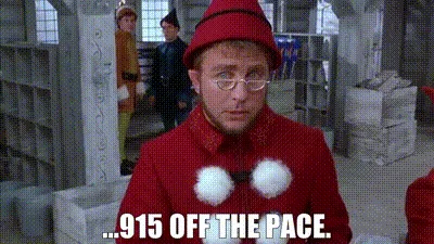 The image shows a still from the movie 'Elf' featuring actor Will Ferrell as Buddy the Elf, wearing a red elf costume with…