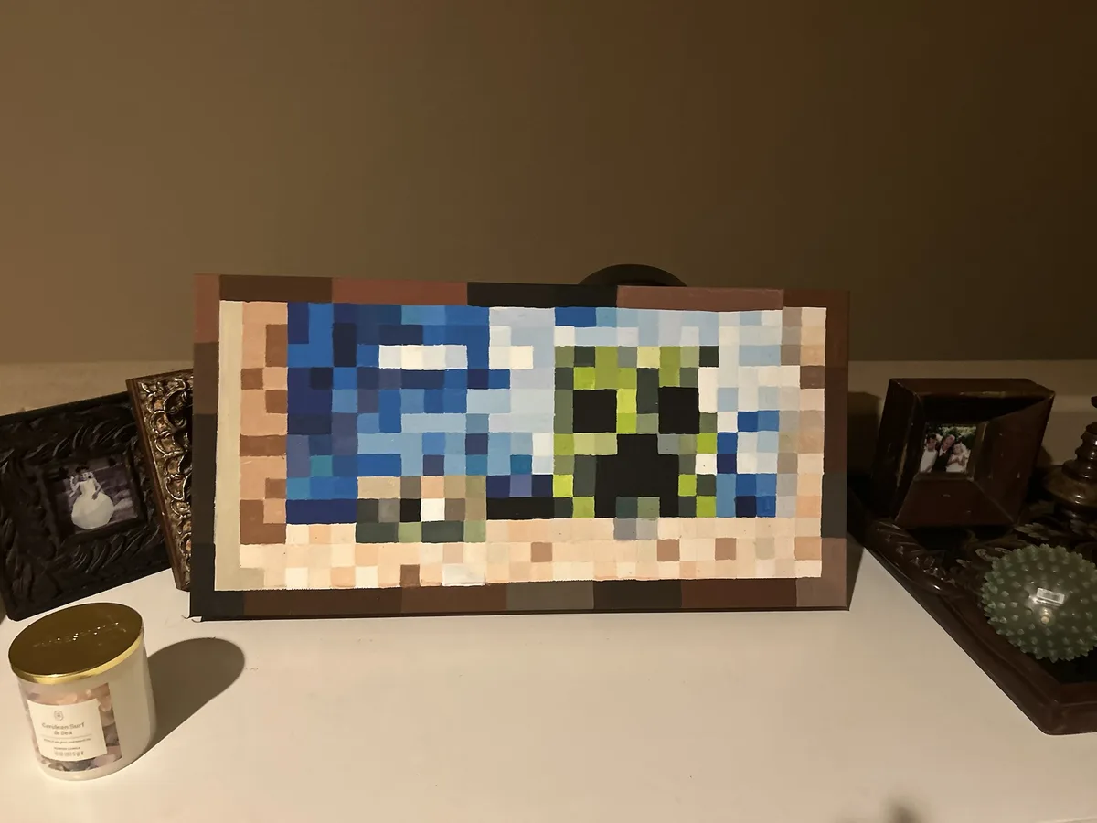 A handmade pixel art painting of SpongeBob SquarePants, rendered in a blocky, Minecraft-style aesthetic, sits on a white…