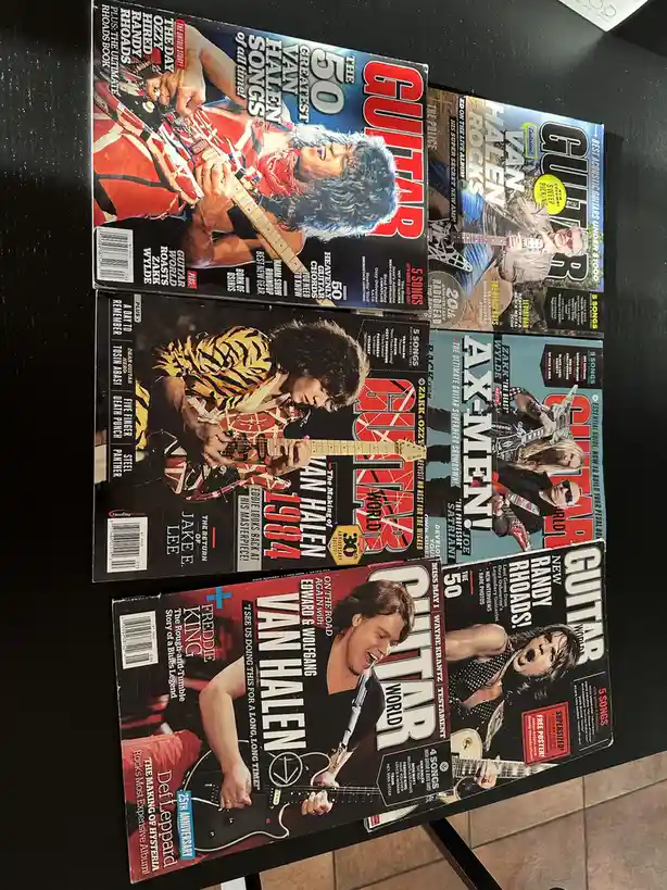 Six Guitar World magazine covers are arranged on a dark surface, each featuring a different Van Halen member or theme, such…