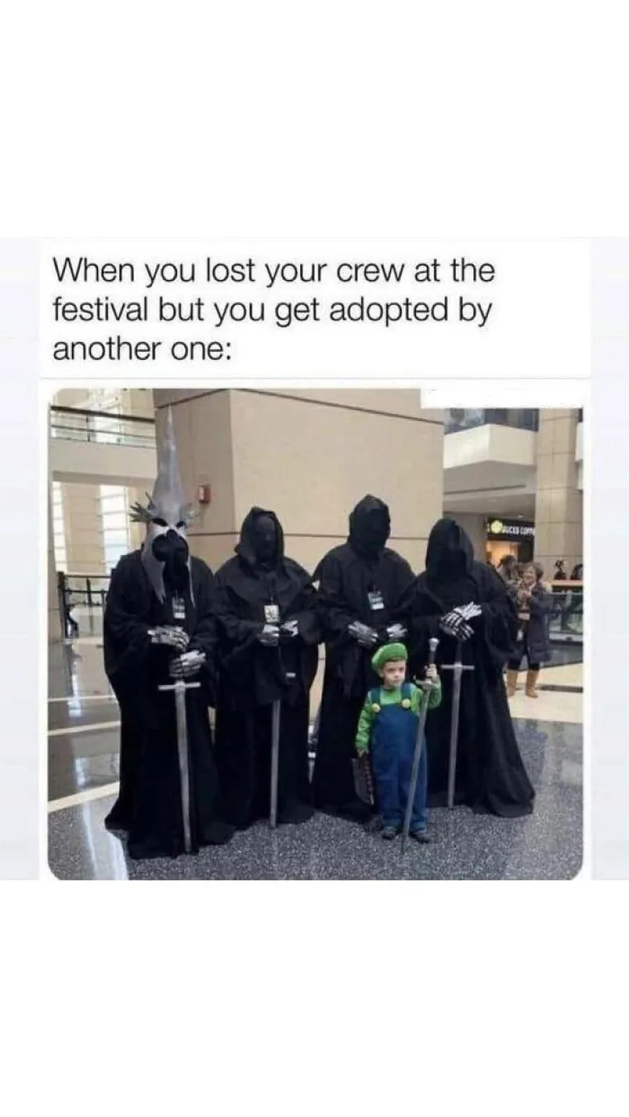 A small child dressed as Luigi stands in front of four tall figures in black hooded robes and masks, each holding a sword…