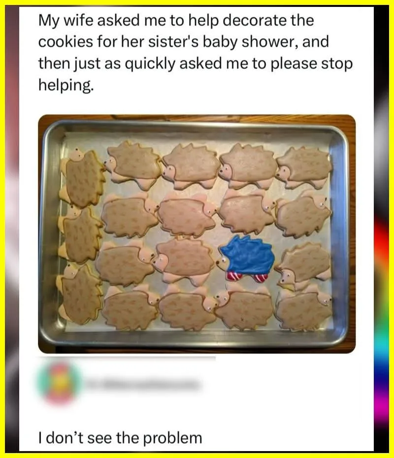 A metal baking tray holds numerous hedgehog-shaped cookies decorated with brown and pink icing. One cookie stands out as a…
