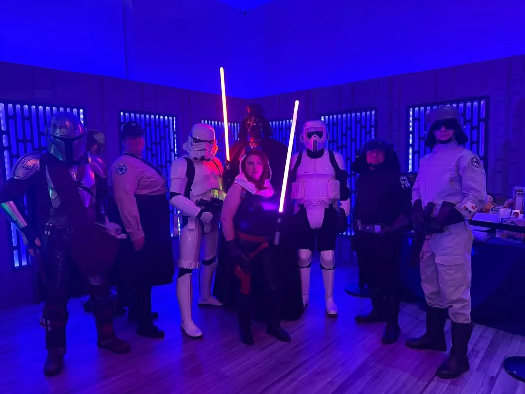 A group of people dressed in Star Wars costumes, including Darth Vader, Stormtroopers, and other characters, pose together…