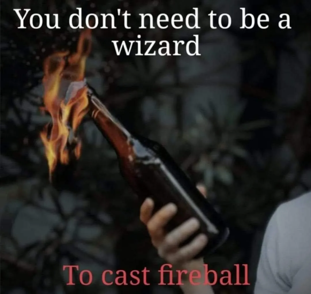 A person holds a brown glass bottle with its neck engulfed in bright orange flames, implying a fireball spell. The text at…