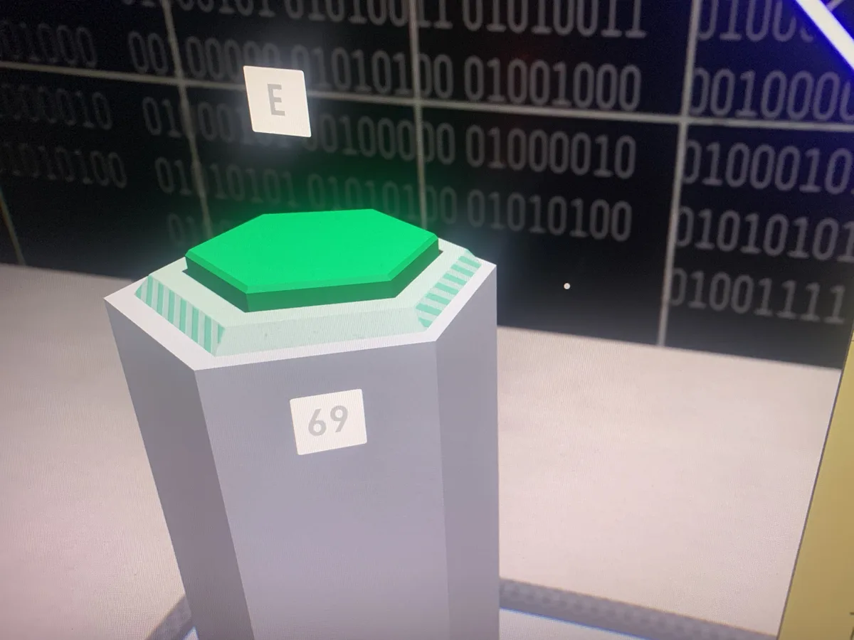 A green hexagonal button sits atop a gray pedestal labeled '69', with a floating letter 'E' above it. The background…