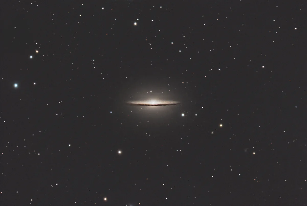 A side-view photograph of a spiral galaxy, appearing as a bright, flat disc with a central bulge, set against a dark sky…