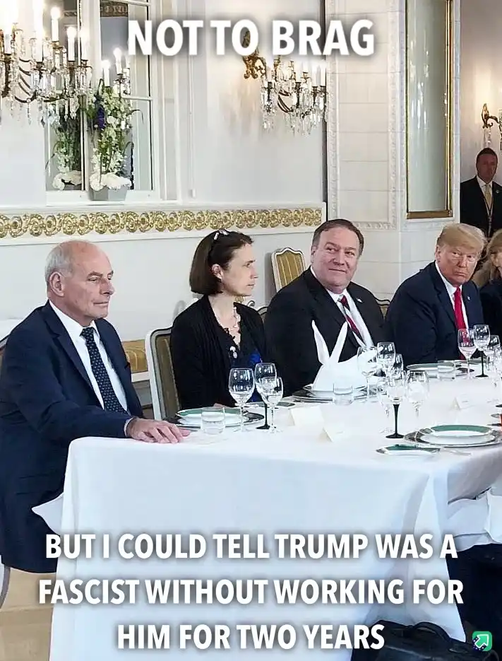 A formal dinner scene with several people seated at a long table with white tablecloths and glassware. The man on the far…