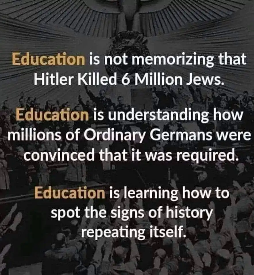 A black-and-white historical photograph shows a large crowd of people in a formal hall, many raising their right arms in a…
