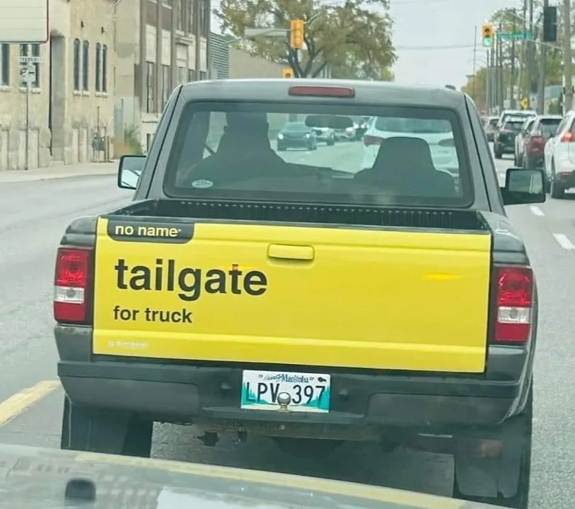 The rear view of a black pickup truck with a bright yellow tailgate panel that has the text 'no name tailgate for truck'…