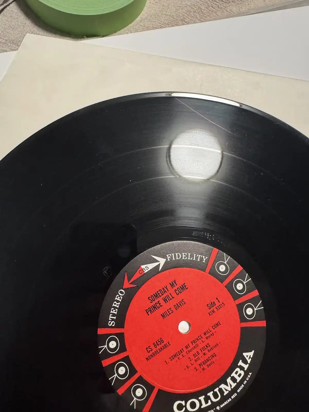 A close-up photo of a black vinyl record with a red and black Columbia label, showing the album title 'Someday My Prince…