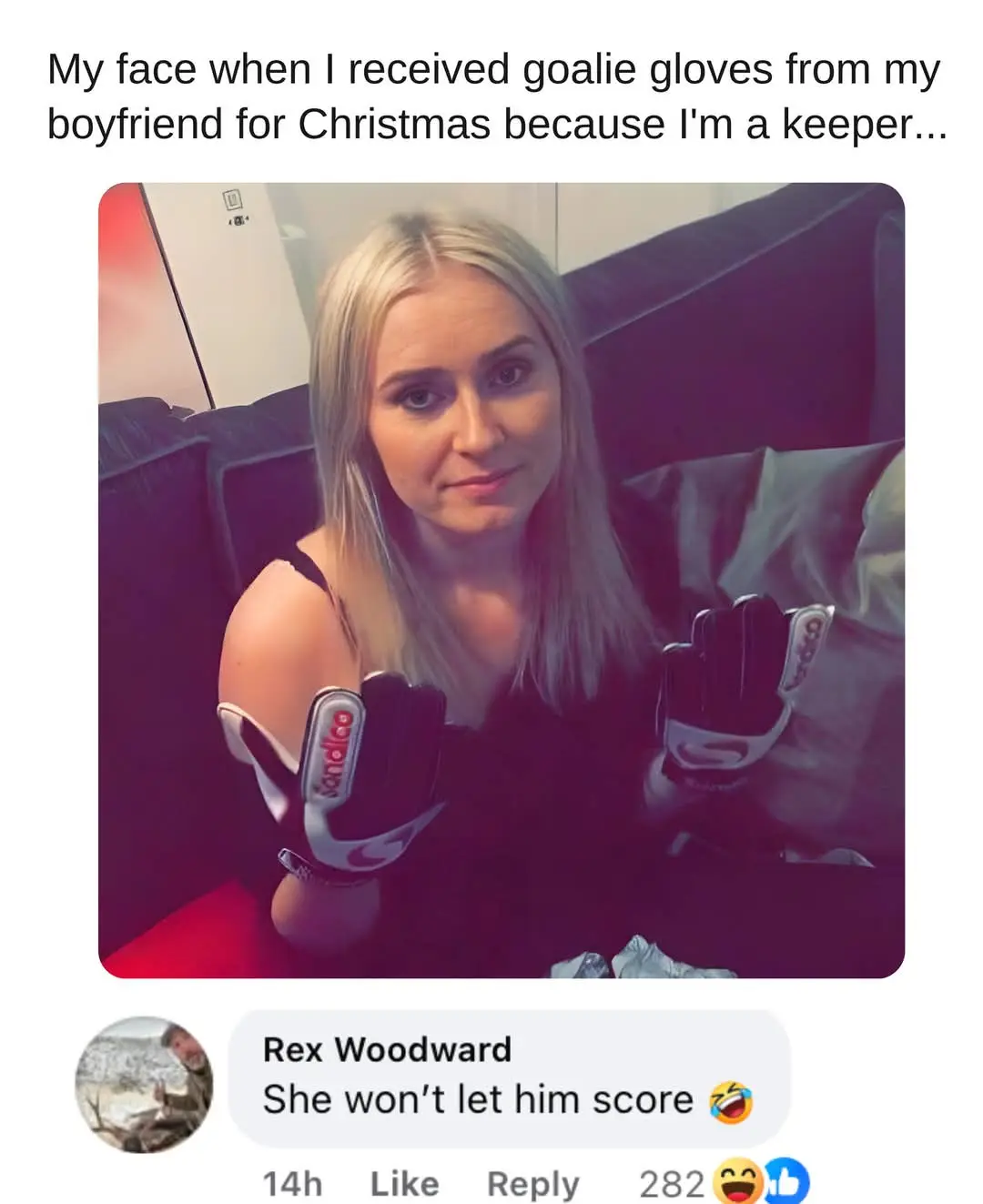 A woman with blonde hair sits on a couch holding up a pair of black and white goalie gloves, looking at the camera with a…