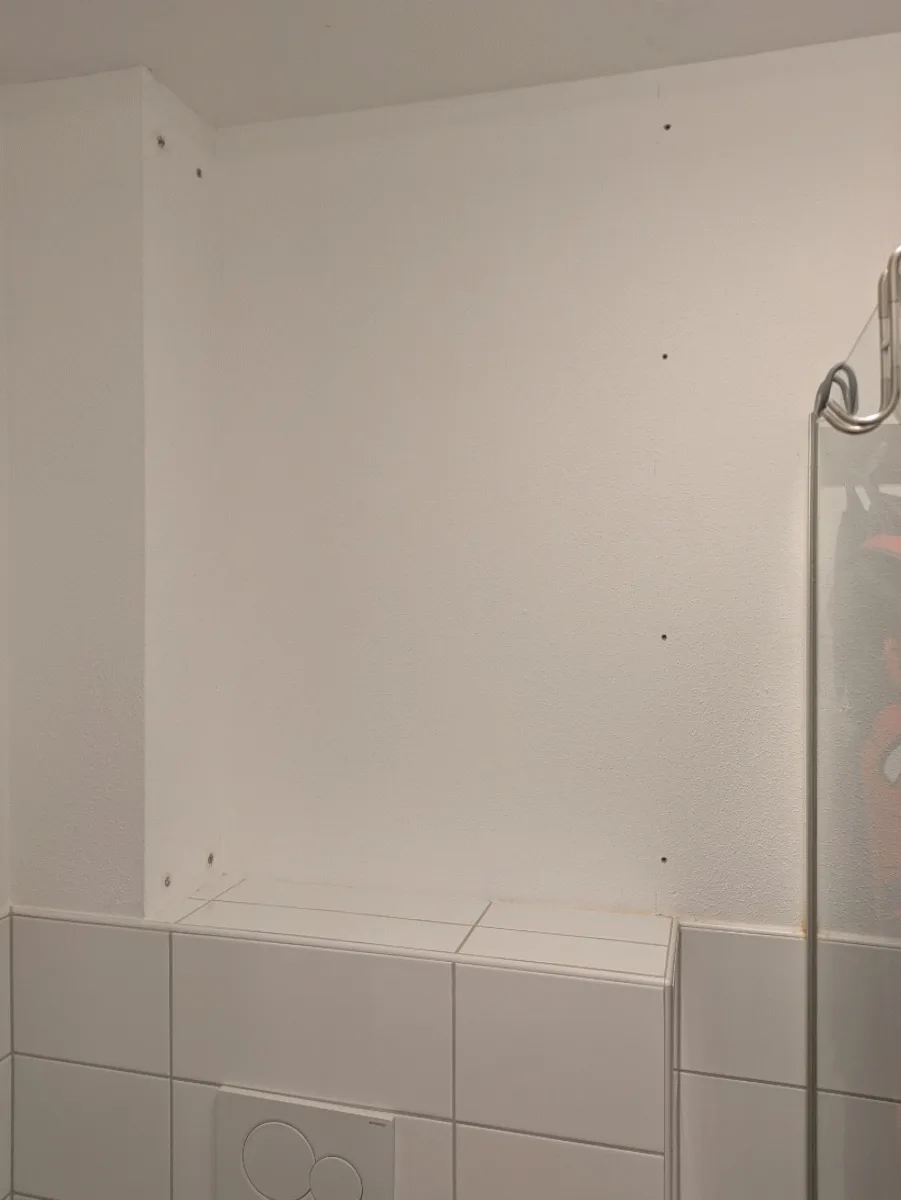 A three-panel image shows the step-by-step construction of a wooden built-in cabinet in a tiled bathroom corner. The first…