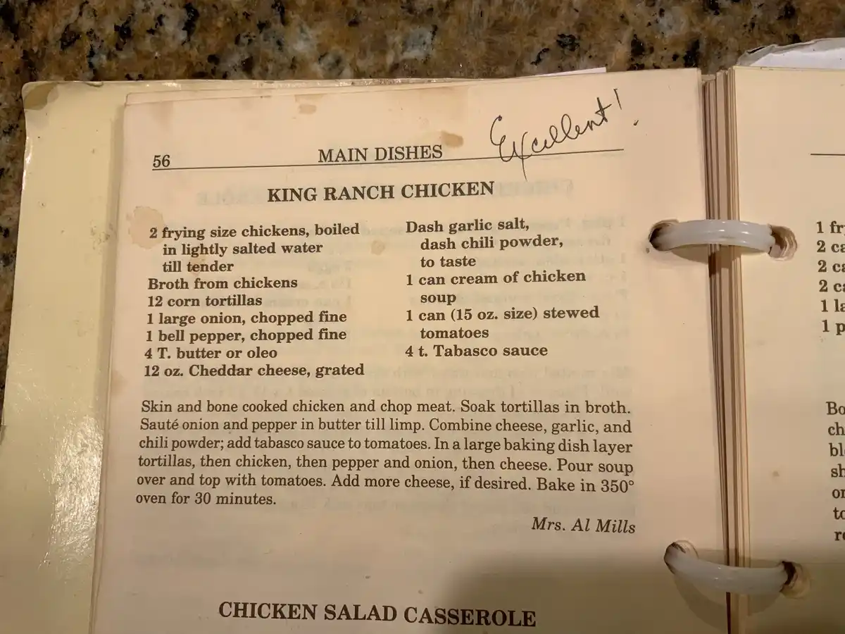 A close-up of a vintage recipe book open to page 56, showing a recipe for 'King Ranch Chicken' with a handwritten note in…