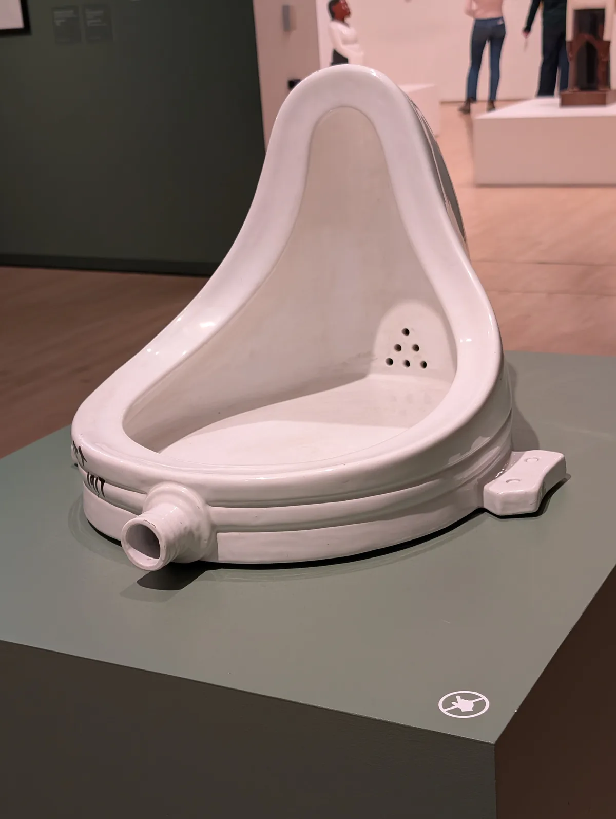 A white ceramic urinal, displayed on a pedestal in a museum gallery, is shown with the overlaid text 'ready for the museum'…