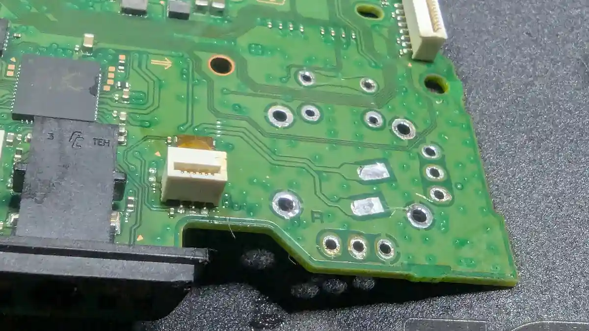 A close-up photo of a green circuit board with various electronic components, solder points, and traces. The board is…