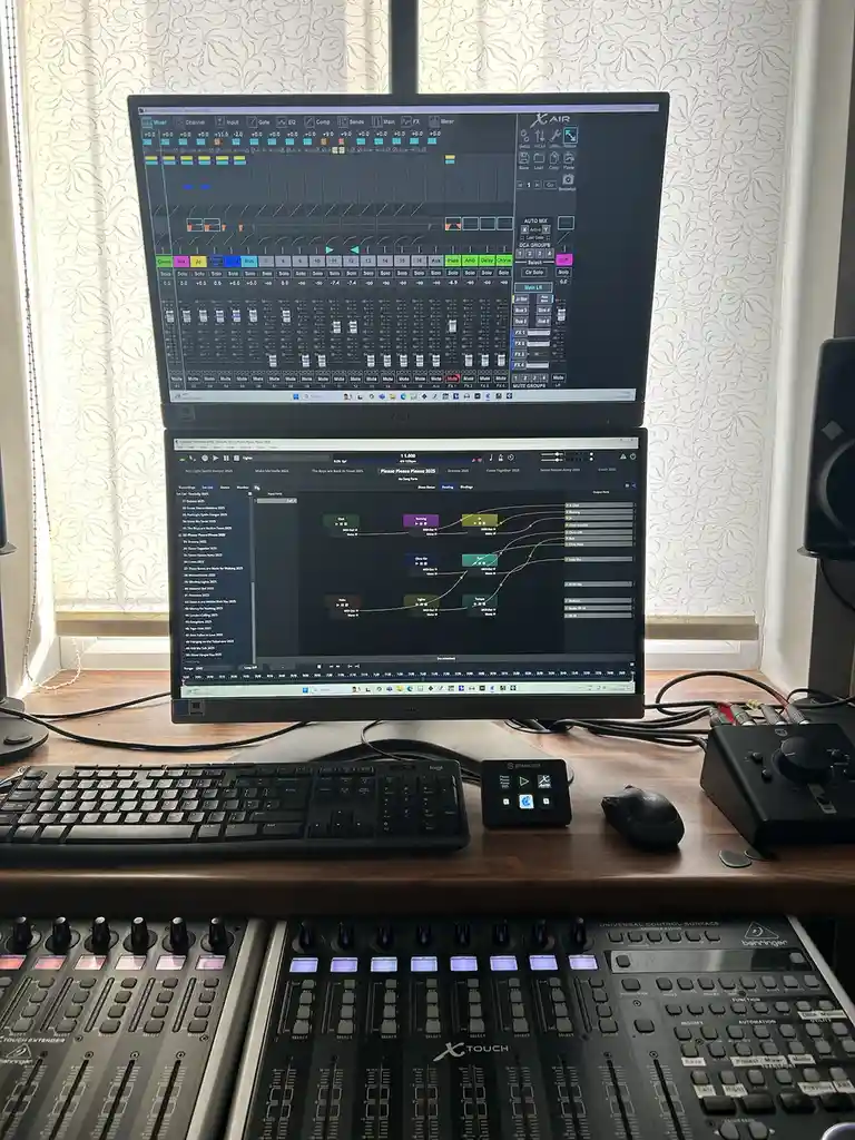 A photo of a professional audio mixing setup with two stacked monitors displaying complex digital audio workstation software…