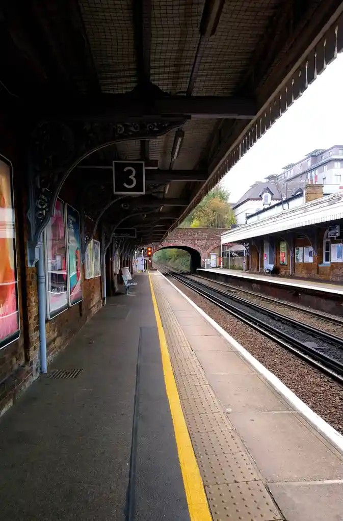An empty train station platform, marked with a large black sign displaying the number 3, stretches into the distance…