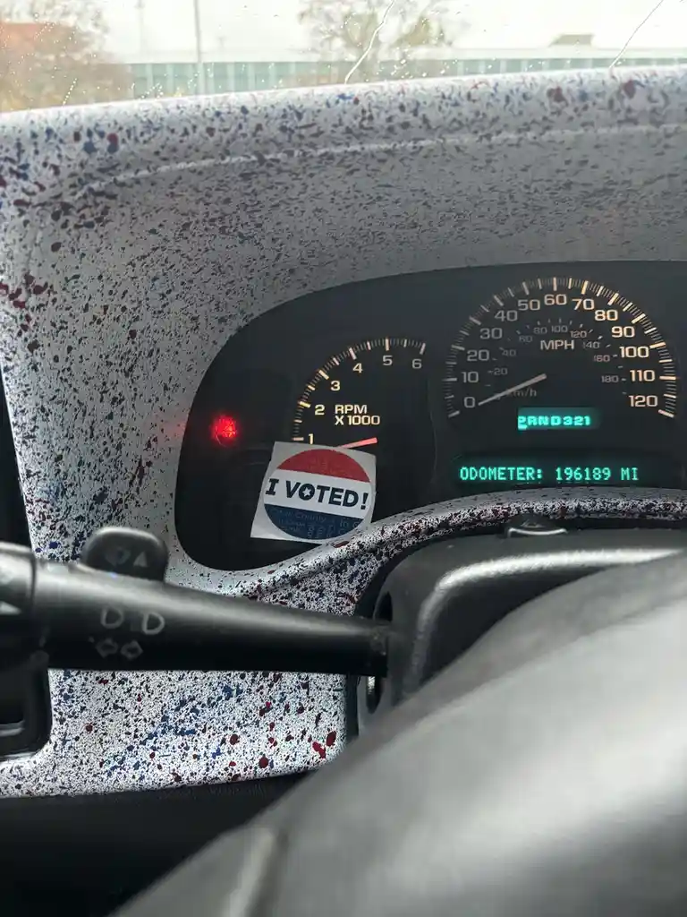 A close-up photo of a car's dashboard with a speckled gray interior, showing a speedometer, tachometer, and digital odometer…