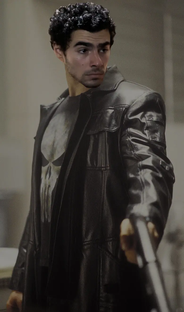 A man with curly dark hair and a serious expression is shown wearing a black leather jacket over a t-shirt with the Punisher…