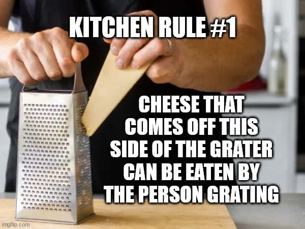 A person is grating cheese using a metal box grater, holding the cheese block with one hand and the grater with the other…