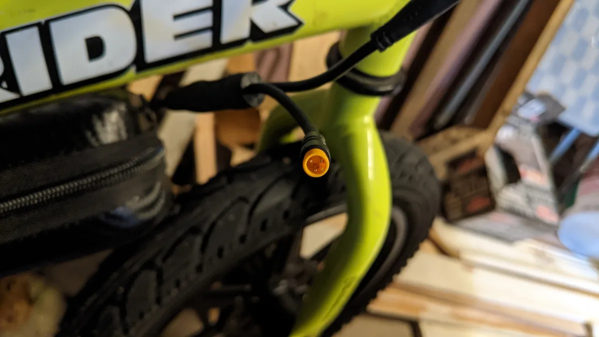 A close-up photo shows a bright lime-green bicycle frame with the brand name 'RIDER' visible. A black cable with a yellow…