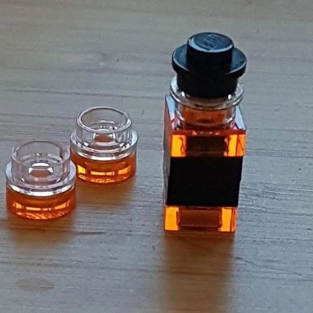 three small glass containers with amber liquid sit on a wooden surface, one larger bottle with a black cap and a black label…