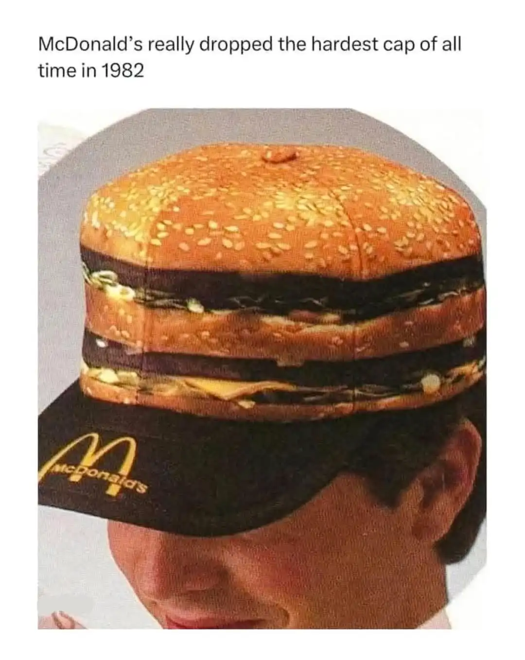A person wears a black McDonald's cap with the golden arches logo, but the cap's top is designed to look like a large…