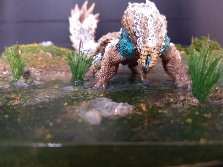 A detailed figurine of a fantasy monster with brown, spiky, textured skin and blue armor-like plates around its neck and…