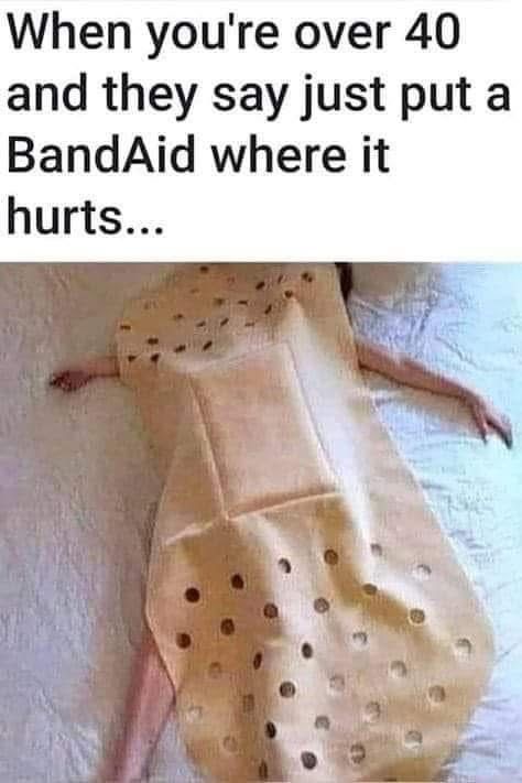 A person is lying on their back on a bed, covered by a large, beige adhesive bandage with numerous circular holes cut out…