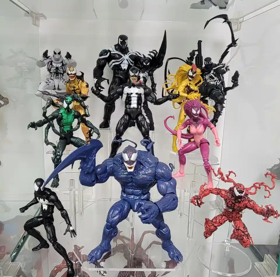 A collection of various Venom and symbiote-themed action figures displayed in a clear acrylic case, featuring multiple color…